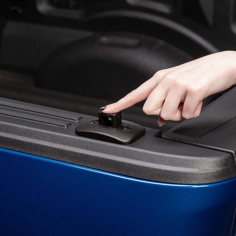 A hand pressing the Push-Up Tie-Down anchor in a truck bed for secure cargo fastening.