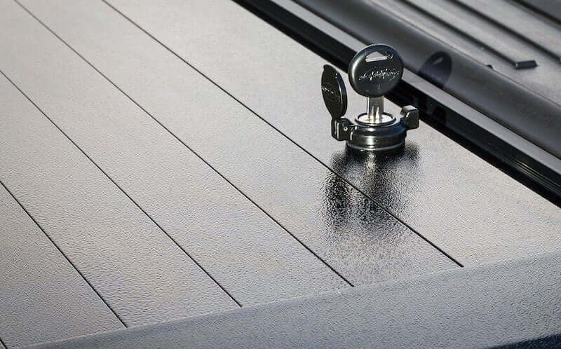 Pace Edwards Tonneau Cover Lock on a black truck bed with secure lock mechanism for cargo protection.