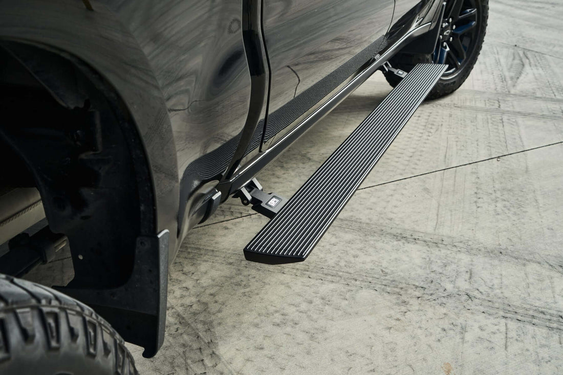 Black power running board deployed beside a black pickup truck, one of the best truck running boards for tall trucks