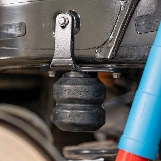 Timbren rubber helper spring installed between the frame and rear axle of a pickup truck, next to a blue shock