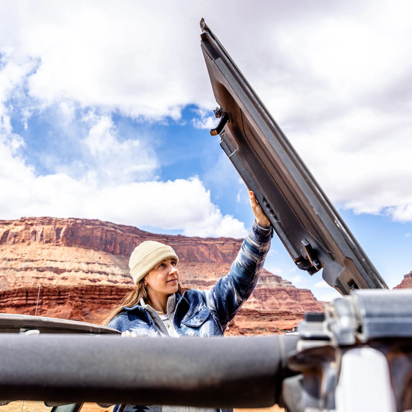 Woman using Jeep JT Gladiator Freedom Panel storage to secure roof panels outdoors.